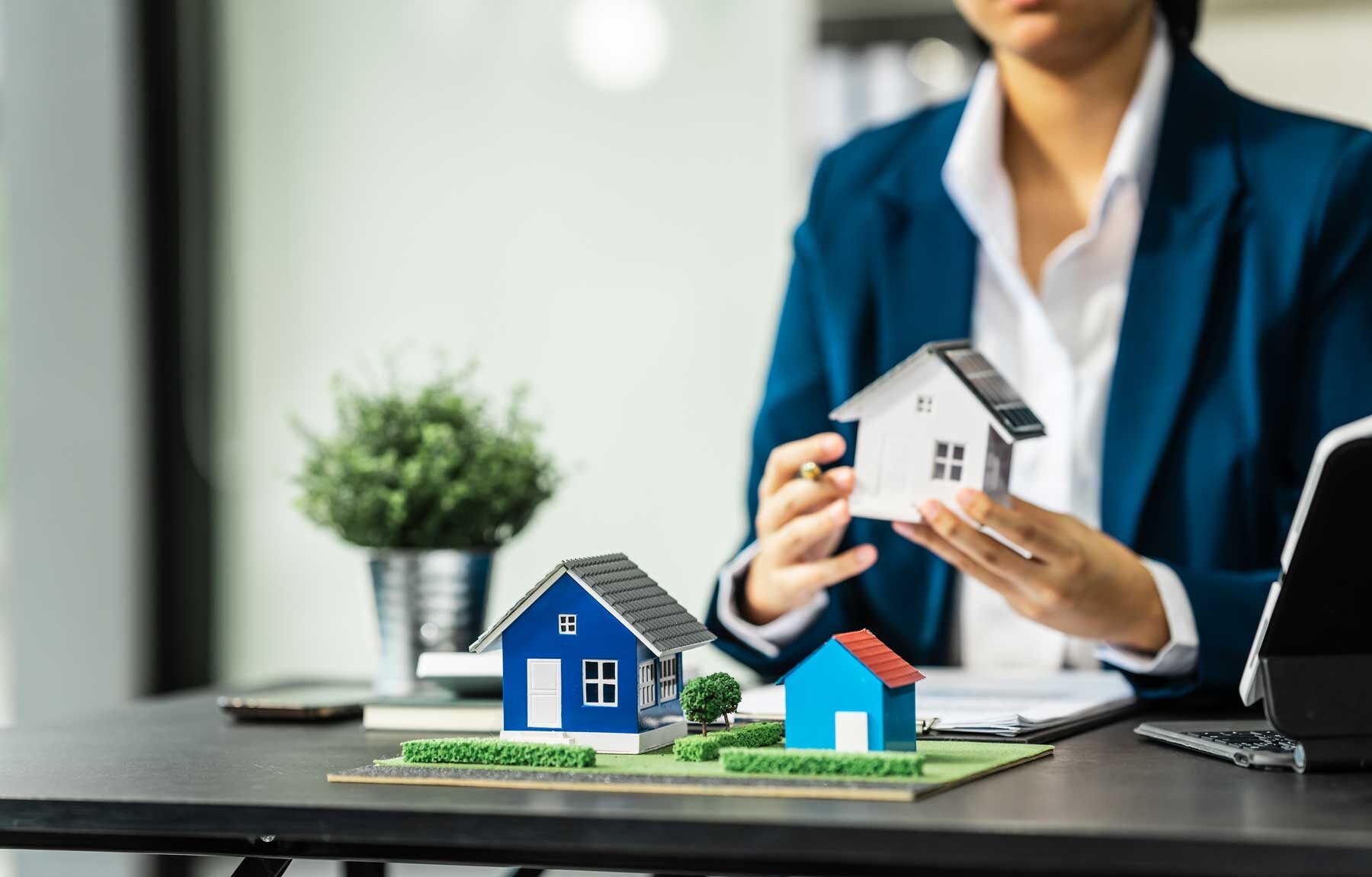 Mujer de bienes raices sosteniendo prototipo de casa en Puebla